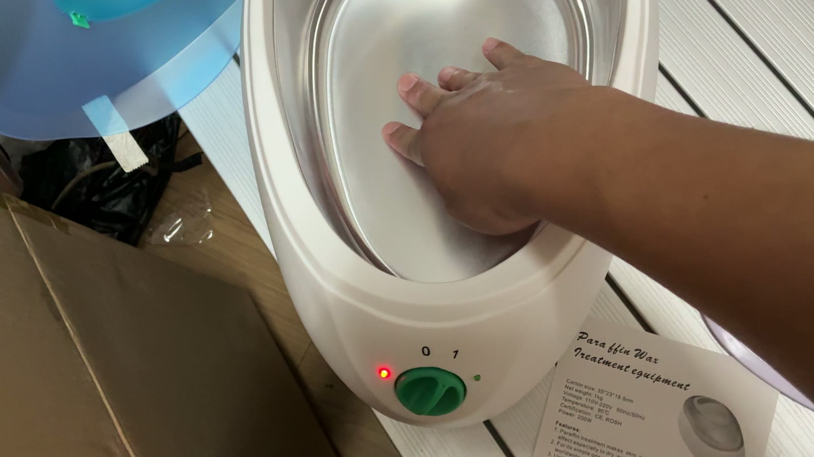 Paraffin wax warmer powered on during inspection in Yiwu, next to its specification sheet